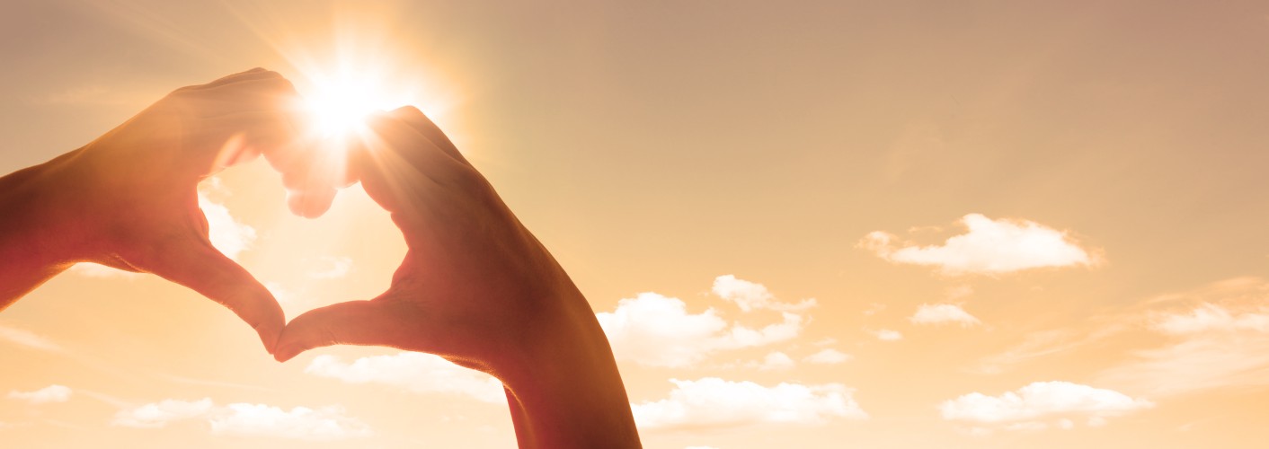 Hände zum Herz geformt. Sonne scheint.